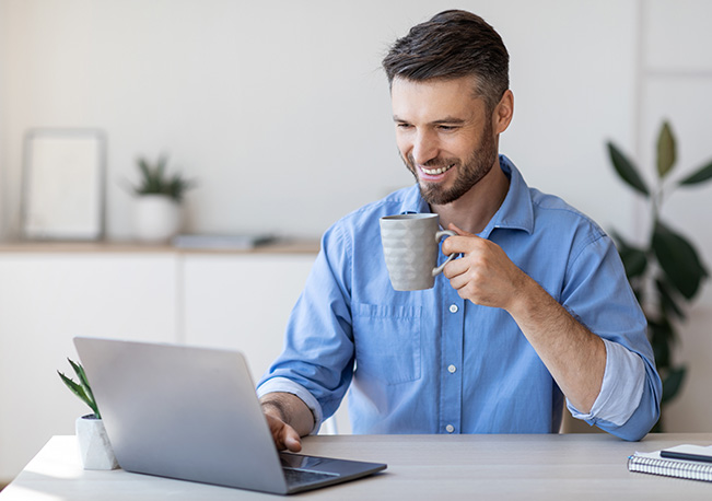 corp-side Man drinking coffee and working on laptop